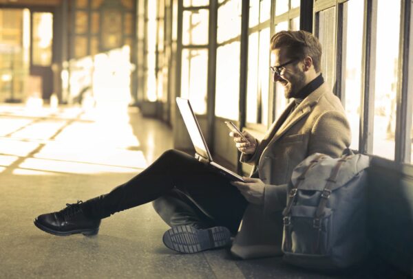 Mann mit Smartphone und Laptop-Rucksack