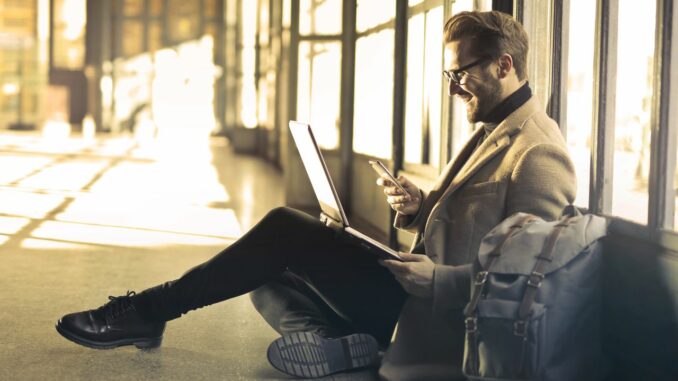 Mann mit Smartphone und Laptop-Rucksack