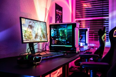Beleuchtetes Gaming-PC-Setup mit Monitor, Tastatur und Headset in einem modernen Raum