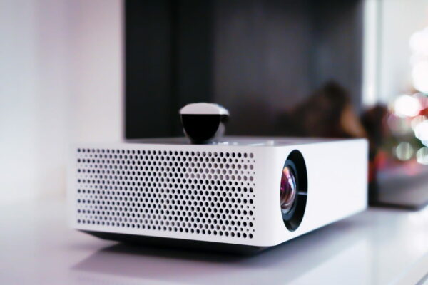 Beamer für das Heimkino einrichten – Essentielles Gerät für ein immersives Filmerlebnis Moderner Beamer für das Heimkino einrichten, Nahaufnahme mit Fokus auf Linse und Lüftungsgitter