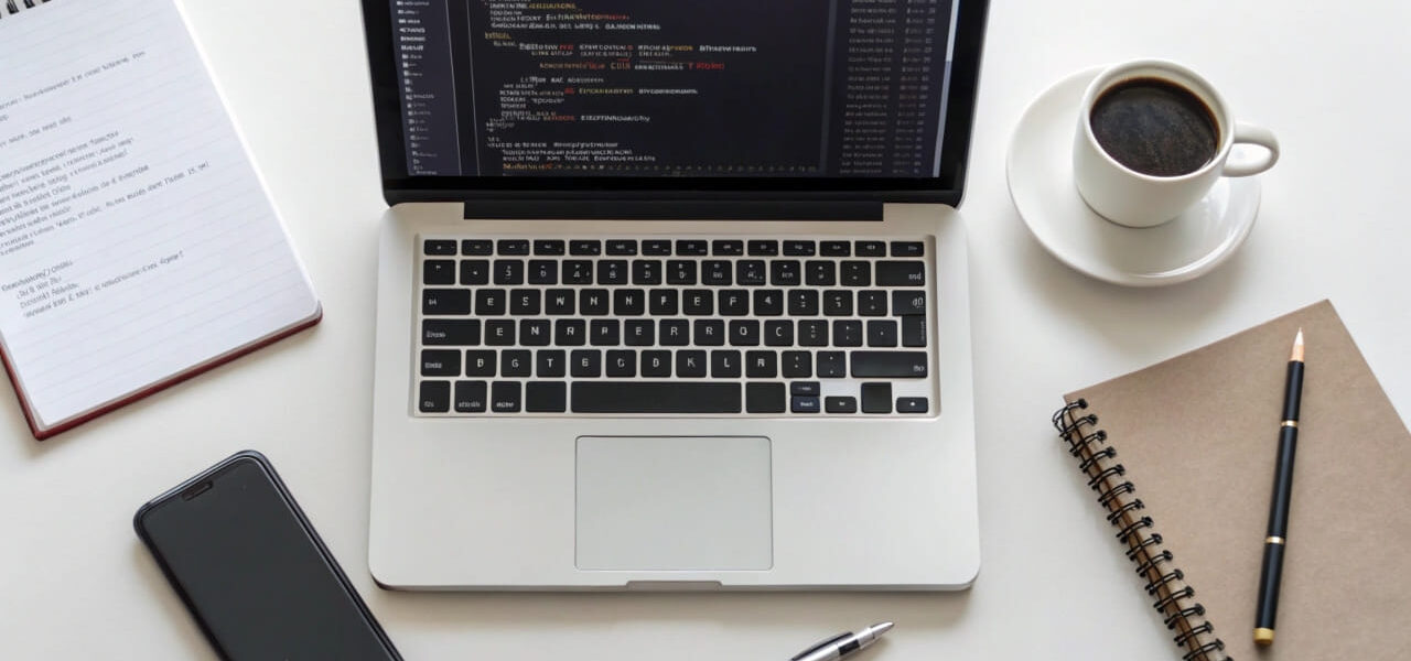 Arbeitsplatz mit Laptop, auf dem HTML- und CSS-Code angezeigt wird – ideal für Einsteiger in die Webentwicklung.