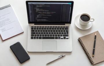 Arbeitsplatz mit Laptop, auf dem HTML- und CSS-Code angezeigt wird – ideal für Einsteiger in die Webentwicklung.