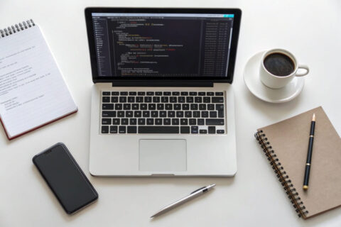 Arbeitsplatz mit Laptop, auf dem HTML- und CSS-Code angezeigt wird – ideal für Einsteiger in die Webentwicklung.