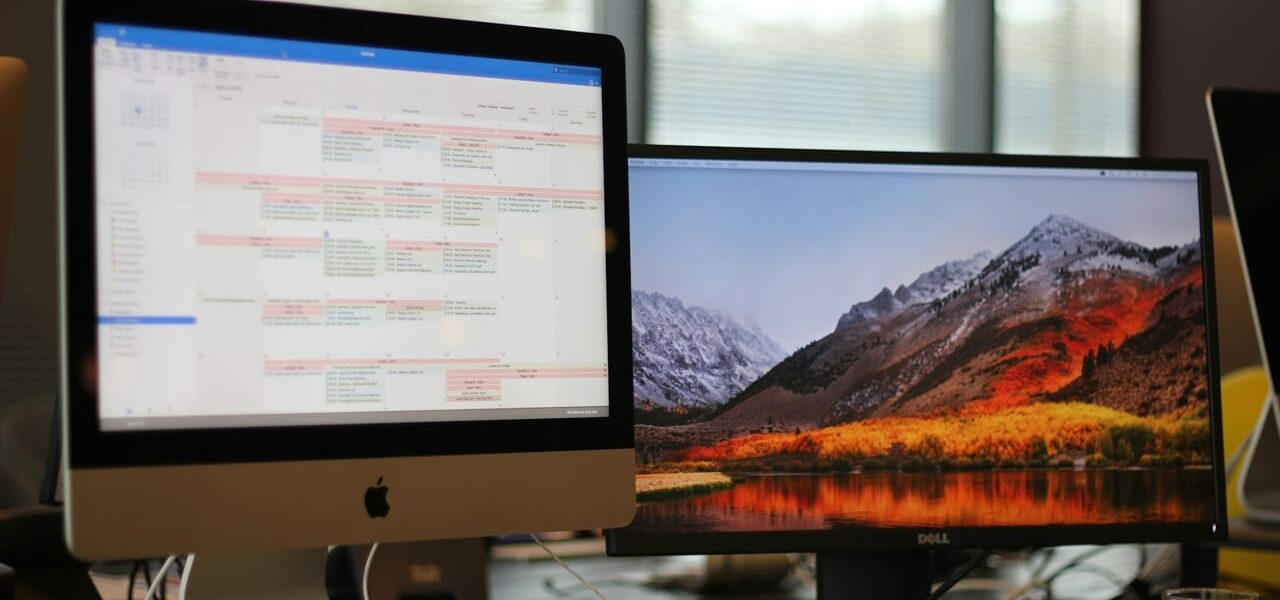 Zwei Bildschirme nebeneinander: Einer zeigt einen Kalender, der andere eine Landschaft, ideal für produktives Arbeiten.