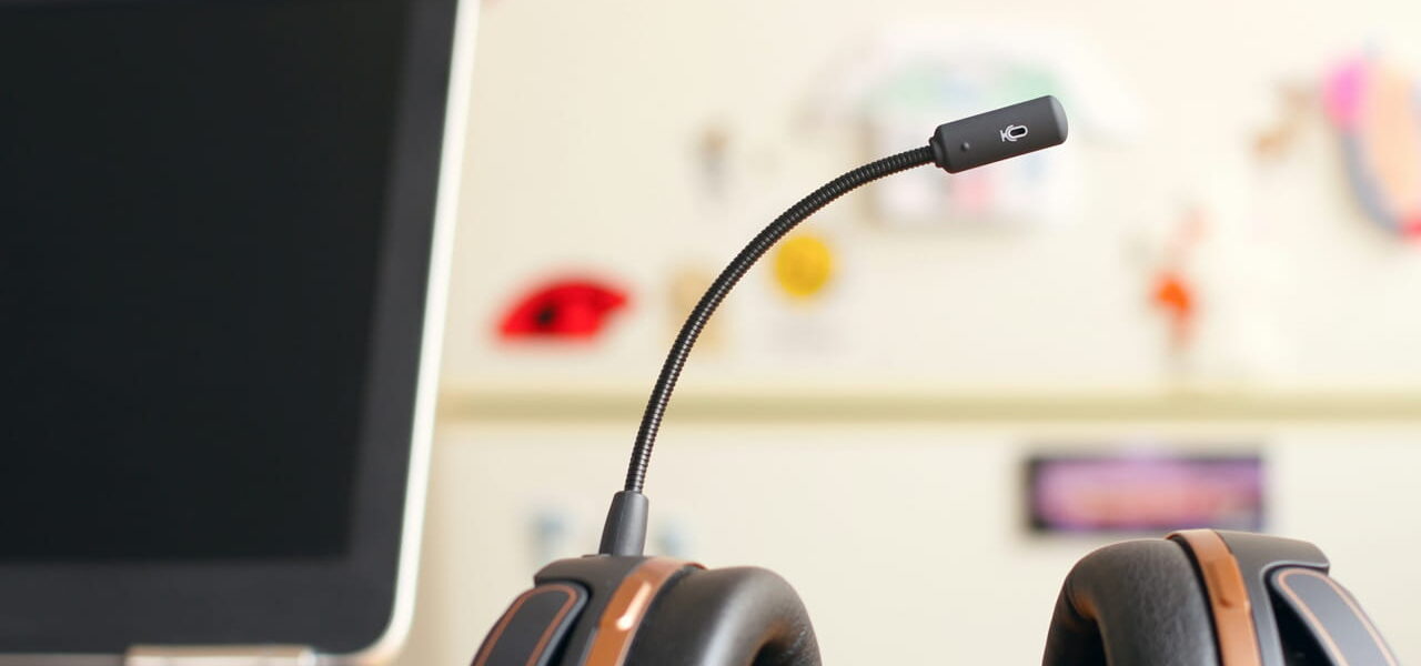 Ein Headset mit Mikrofon auf einem Schreibtisch neben einem Laptop.
