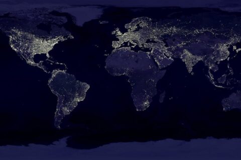 Weltkarte bei Nacht mit globaler Vernetzung – Auswirkungen des AI Act auf internationale KI-Dienste.