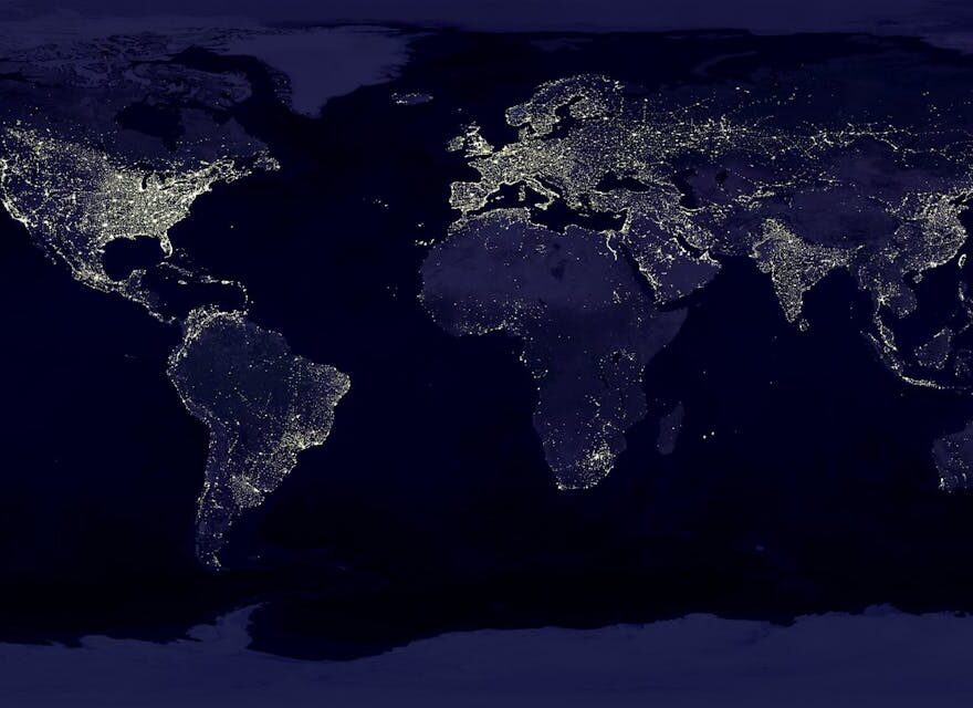 Weltkarte bei Nacht mit globaler Vernetzung – Auswirkungen des AI Act auf internationale KI-Dienste.