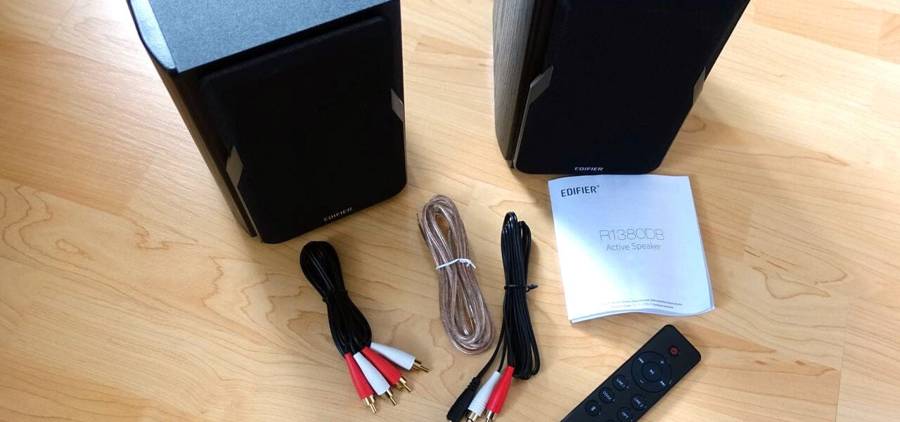 EDIFIER Studio R1380DB 2.0 Regallautsprecher mit Zubehör: Fernbedienung, Kabel, Lautsprecherkabel und Bedienungsanleitung auf Holzboden