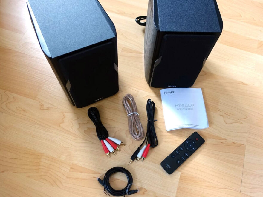 EDIFIER Studio R1380DB 2.0 Regallautsprecher mit Zubehör: Fernbedienung, Kabel, Lautsprecherkabel und Bedienungsanleitung auf Holzboden
