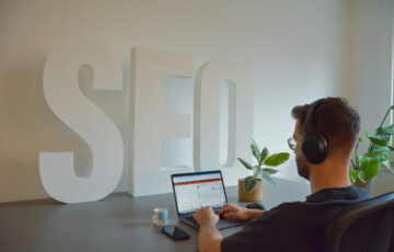 Person arbeitet am Laptop mit SEO-Analyse vor großem SEO-Schriftzug