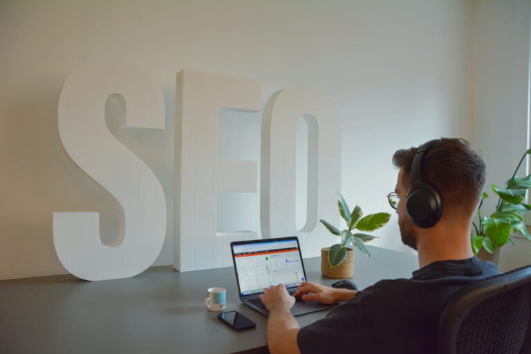 Person arbeitet am Laptop mit SEO-Analyse vor großem SEO-Schriftzug