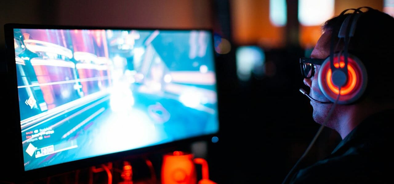 Gamer am PC mit Headset, der ein Spiel mit möglichem Input Lag erlebt