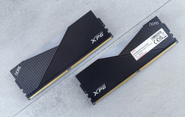 Zwei schwarze XPG DDR5 Arbeitsspeicher Module auf grauem Untergrund.