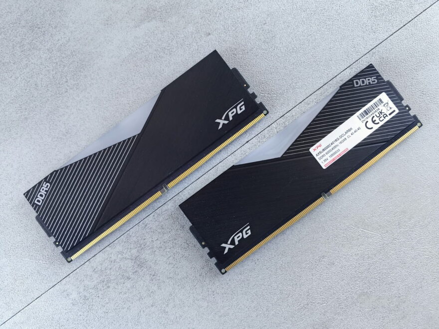 Zwei schwarze XPG DDR5 Arbeitsspeicher Module auf grauem Untergrund.