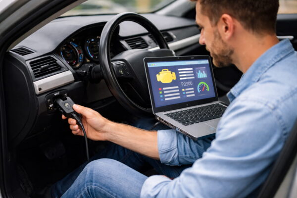 KFZ-Steuergerät auslesen mit OBD2-Adapter und Laptop im Auto während der Diagnose